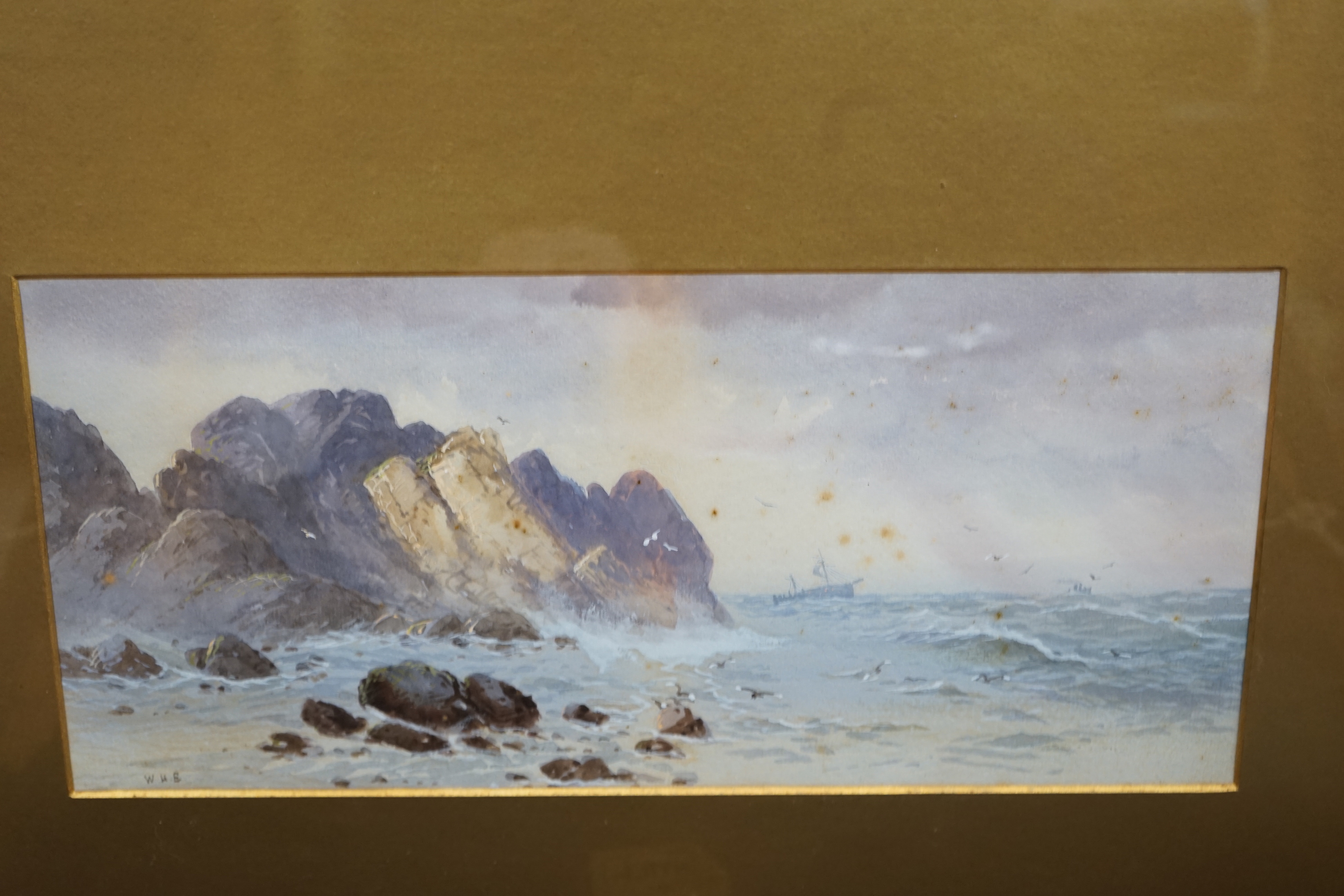 WHE, pair of heightened watercolours, rocky coastal landscapes, signed with monogram, 16 x 36cm